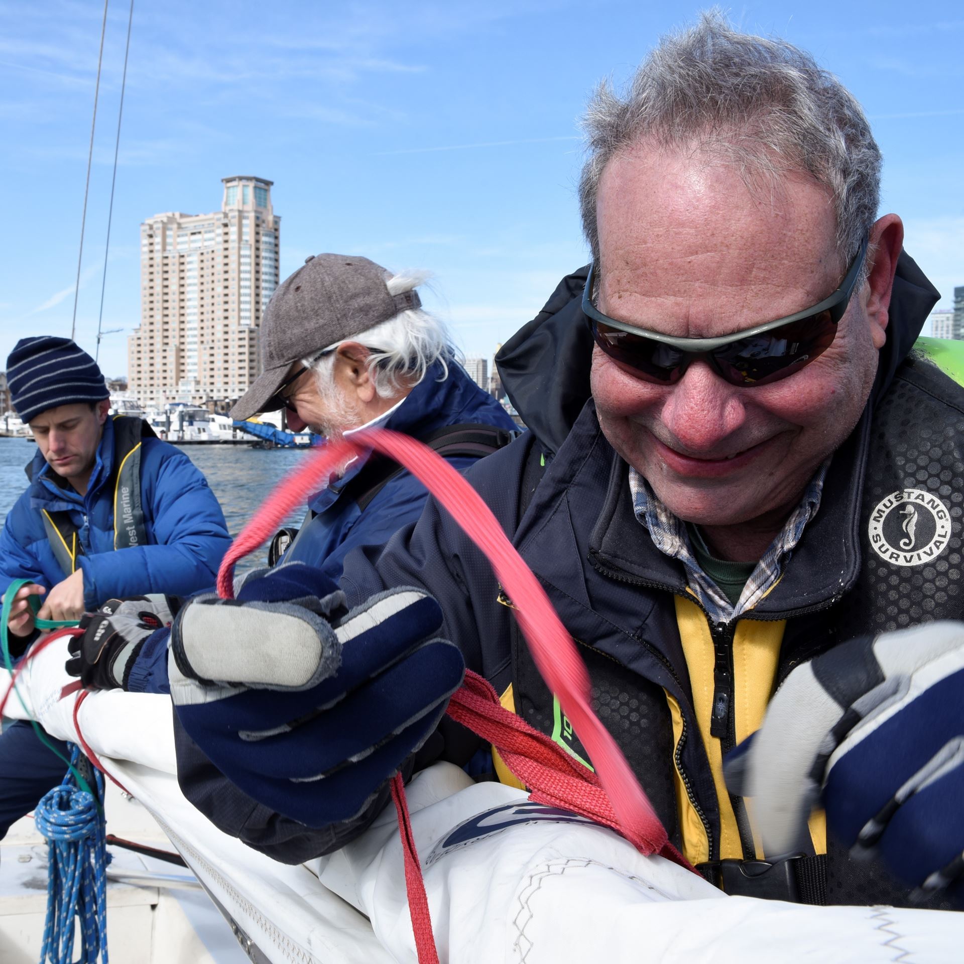 Coach Bruce & Coach Graham help George roll the Sonar mainsail after a spring sail