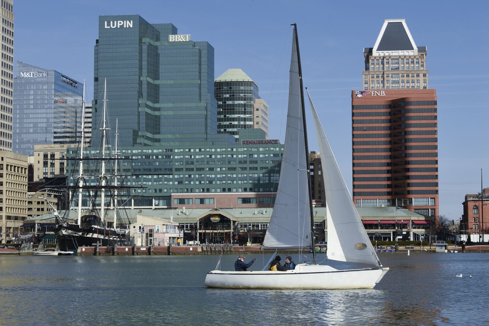 A Sonar sailboat meanders in Baltimore Inner Harbor on a sunny day